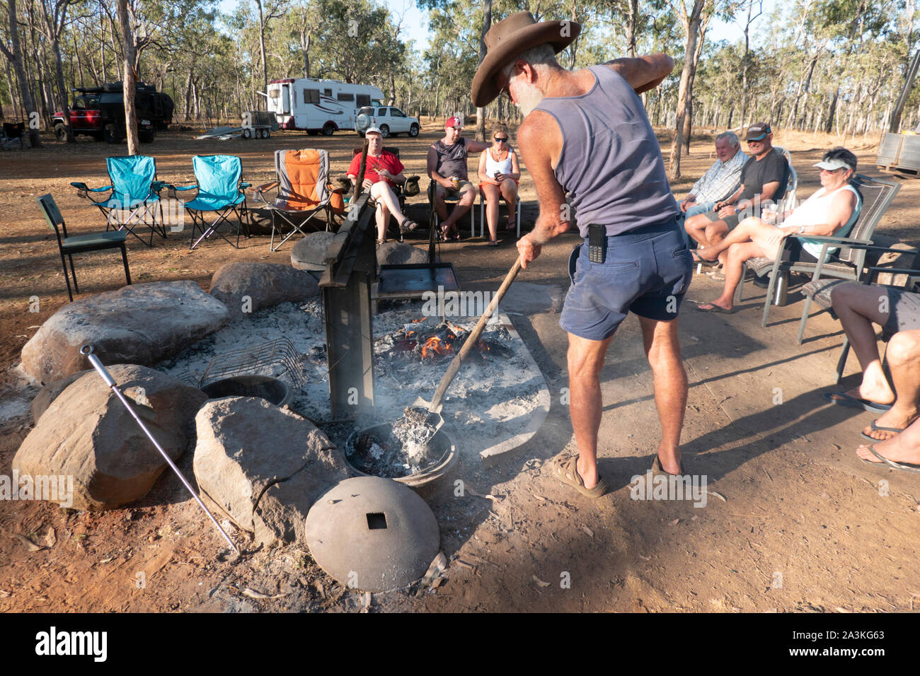 Bushman Kochen in einem Camp Backofen über einem Lagerfeuer, mit Bush Camper sitzen, Mareeba, Queensland, Queensland, Australien Stockfoto