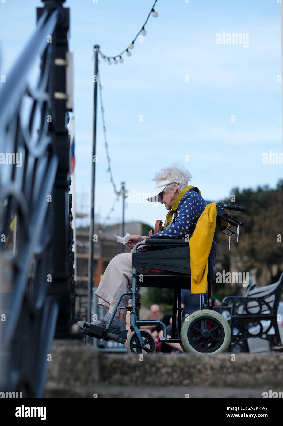 Eine alte Dame im Rollstuhl auf einem direkt am Meer sitzen. Stockfoto