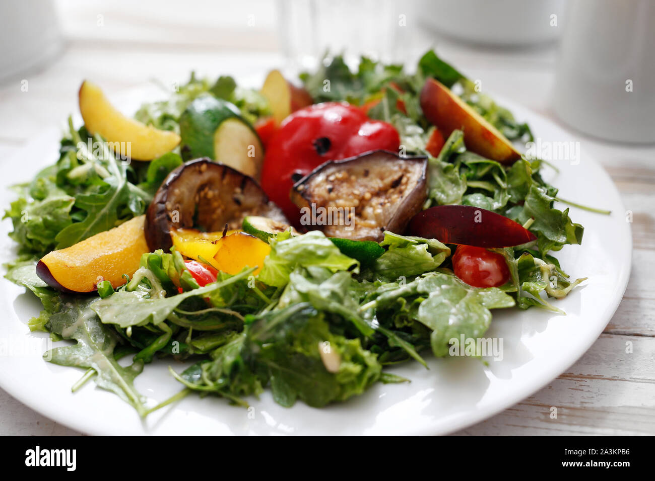 Salat von gegrilltem Gemüse auf Rucolasalat mit Pflaume, Pfirsich und Vinaigrette. Stockfoto