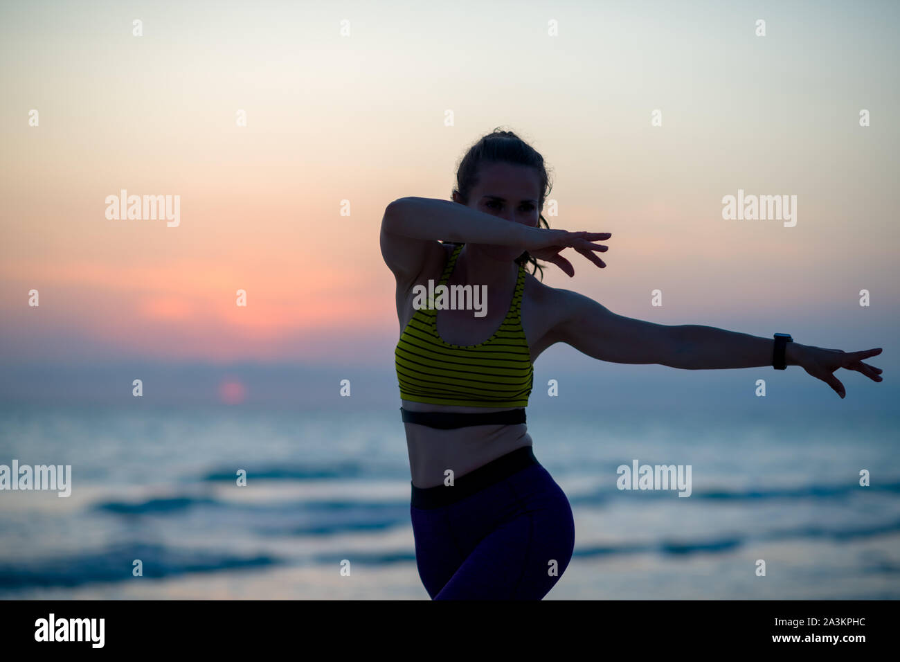 Silhouette von Fitness Sport Frau in Sport Kleidung auf dem Ozean Küste am Abend tun martial arts Training. Stockfoto