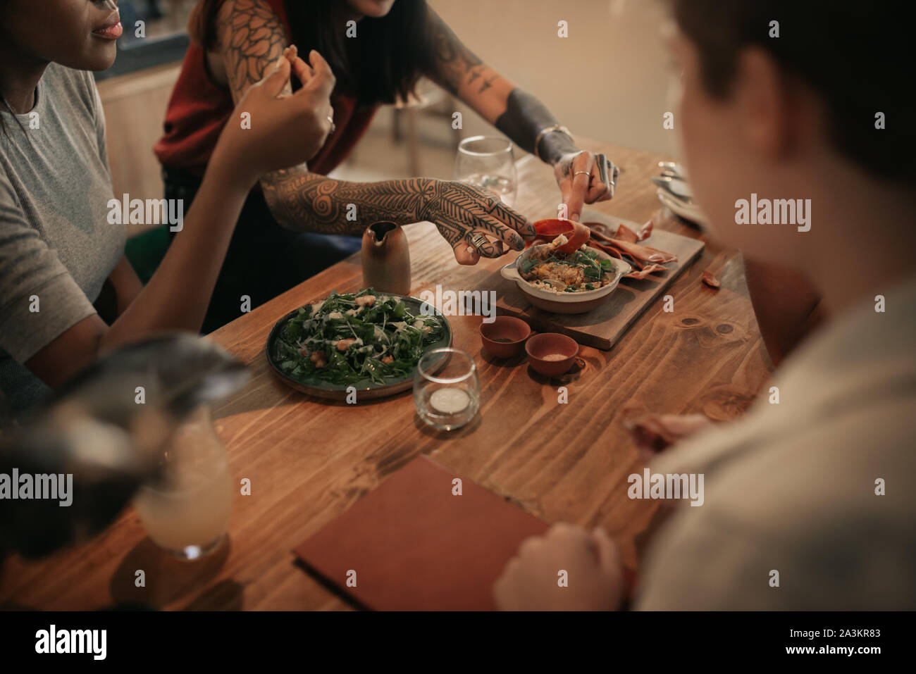 Diverse Freunde an einem bistrotisch gemeinsame Essen sitzen Stockfoto