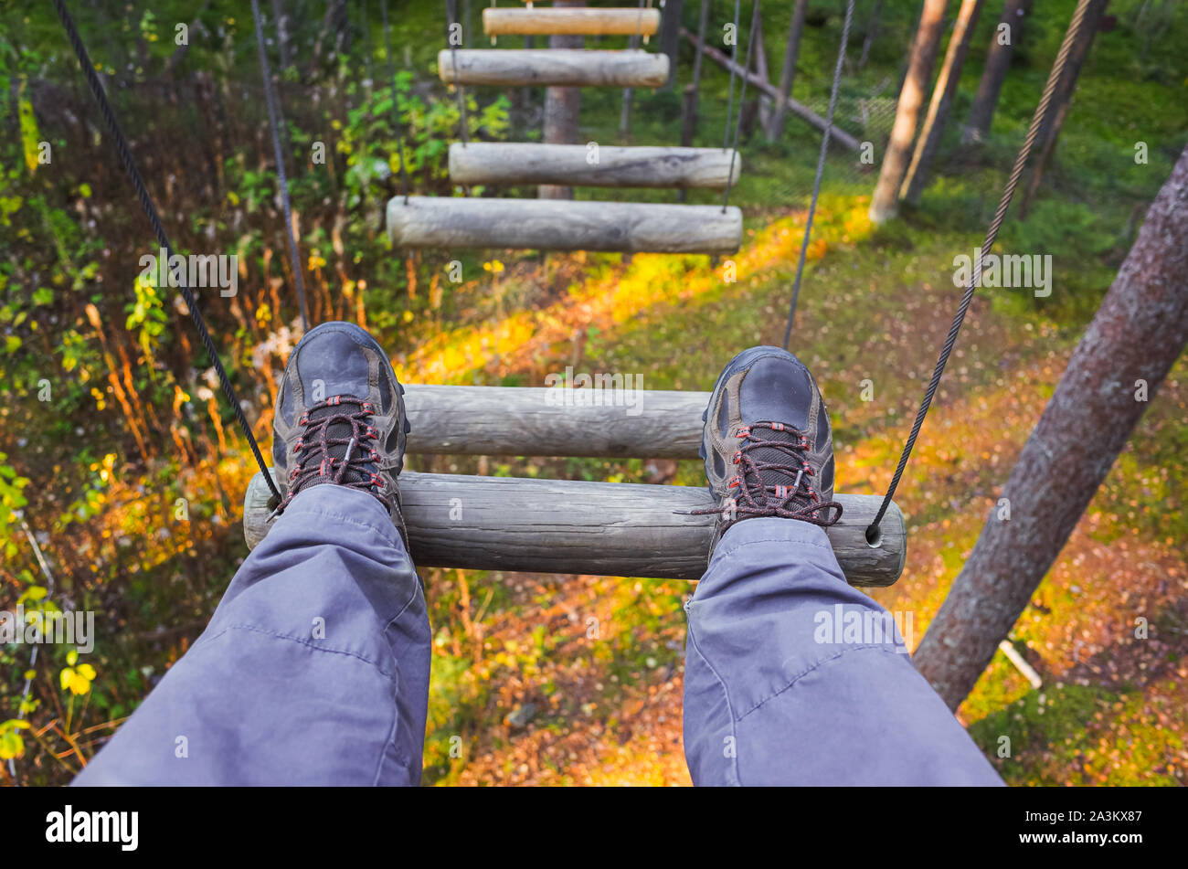 Füße mit sportlichen Schuhen eines Menschen ruht auf hängende Pfad in einem Seilpark Stockfoto
