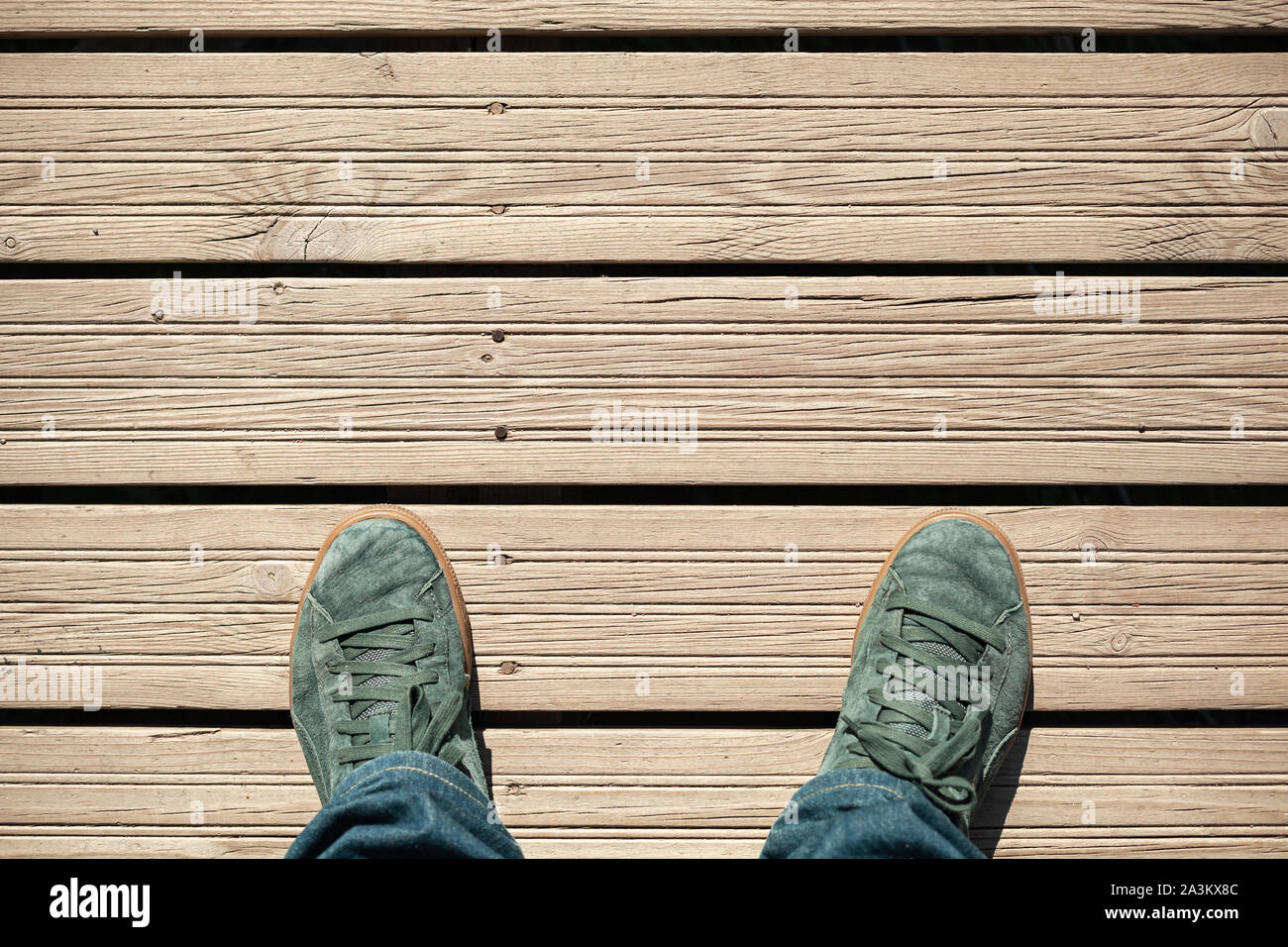 Männliche Füße in Grün sportlich Wildleder Schuhe stehen auf Holzboden, erste Person anzeigen Stockfoto