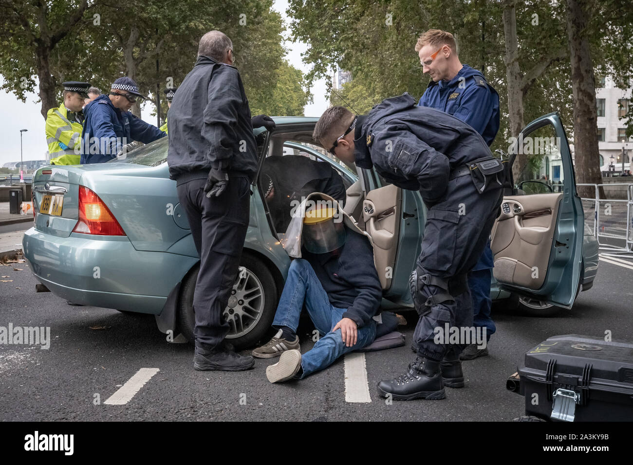 Spezialist" Protest Ausbau Team" der Polizei versuchen frei zu schneiden, eine gesperrte auf demonstrant aus einem Auto geparkt behindern Victoria Embankment, die das Aussterben Rebellion Demonstranten versuchte, von 6 Uhr morgens bis zu besetzen. Die Umweltaktivisten beginnen Sie eine neue Welle von Protest Aktion heute Morgen verursachen Störungen in London, UK. Stockfoto