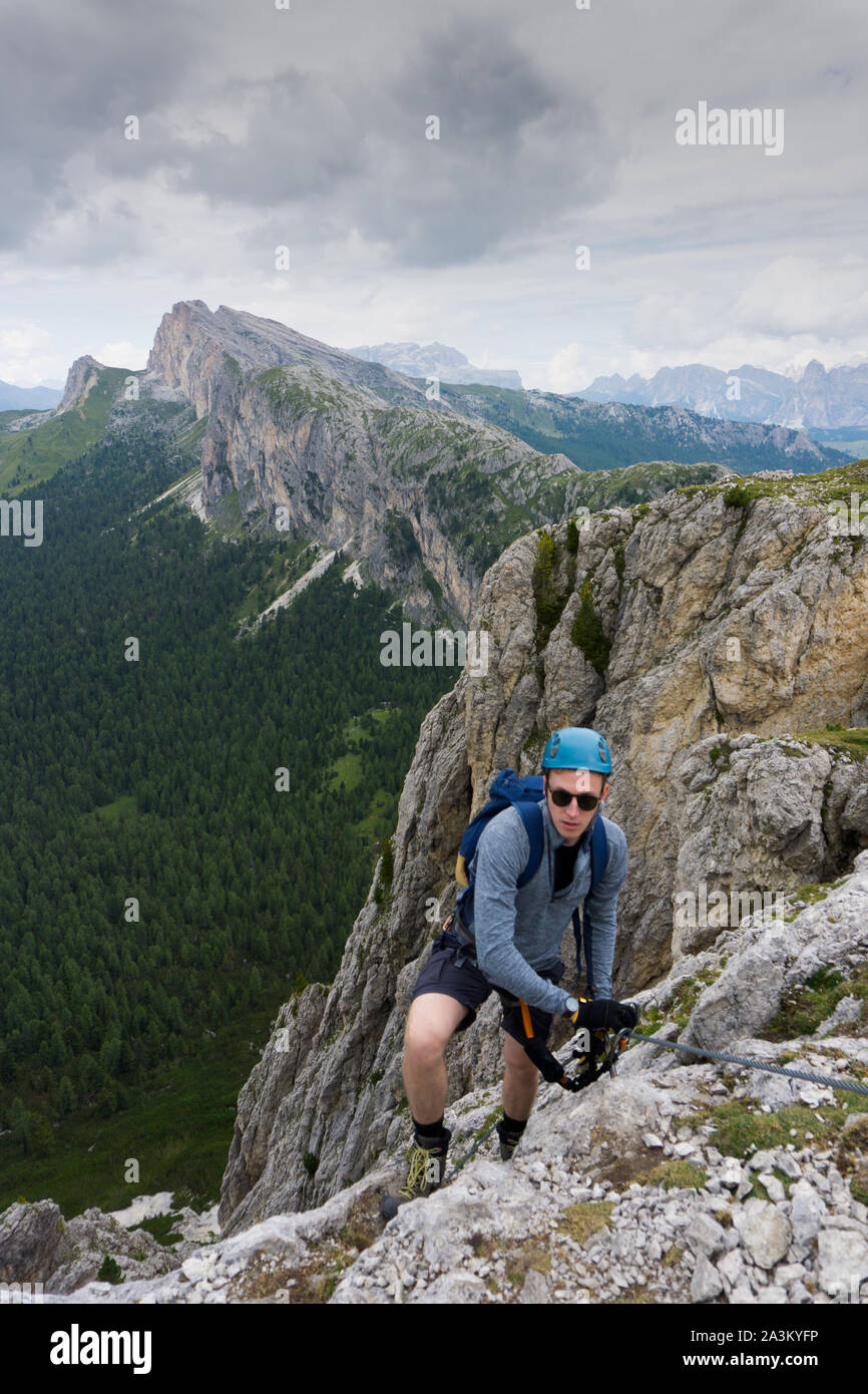Ein Mann in den zwanziger Jahren an einem steilen Klettersteige in den Dolomiten von Alta Badia Stockfoto