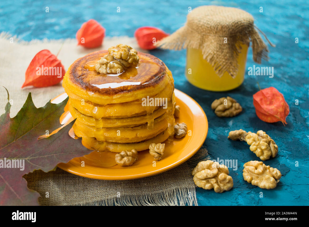 Kürbis Pfannkuchen mit Honig und Nüssen auf blauem Hintergrund. Stockfoto