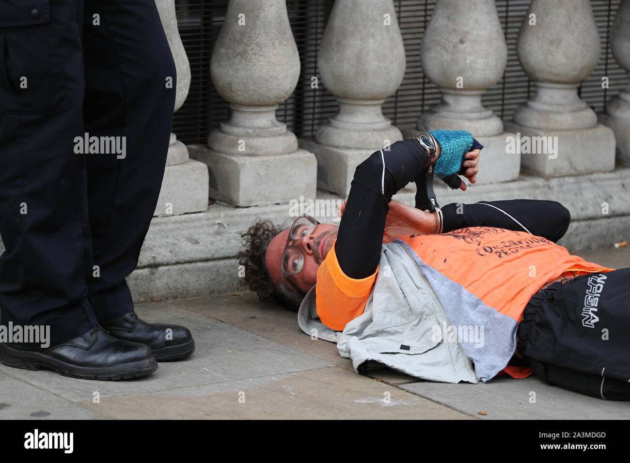 Polizei sprechen zu einem Mann, der sich während einer Aussterben Rebellion Klimawandel Protest in Westminster, London mit Handschellen gefesselt hat. Stockfoto