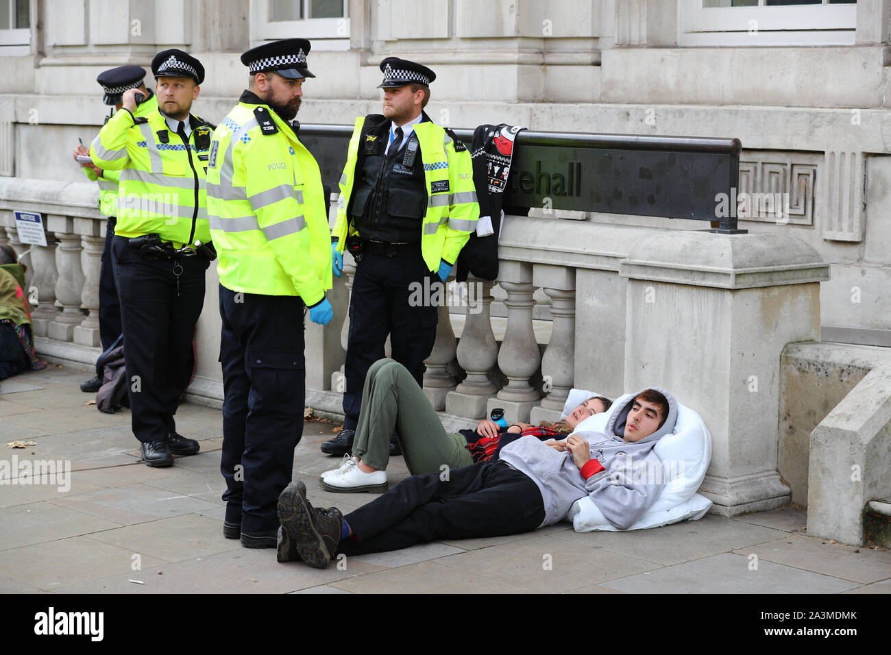 Polizei sprechen Sie mit zwei Demonstranten während einer Aussterben Rebellion Klimawandel Protest in Westminster, London. Stockfoto