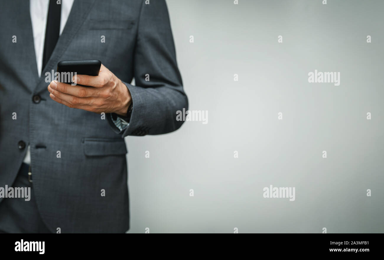 Unternehmer tragen mit Phone auf grauem Hintergrund. Kopieren Sie Platz Stockfoto