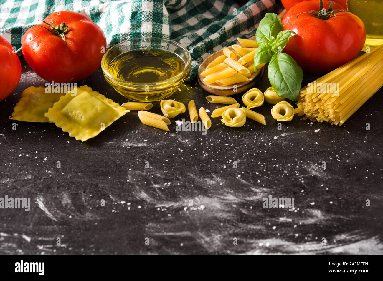 Italienische Pasta und Zutaten. Ravioli, Nudeln, Spaghetti, Tortellini, Tomaten und Basilikum Stockfoto