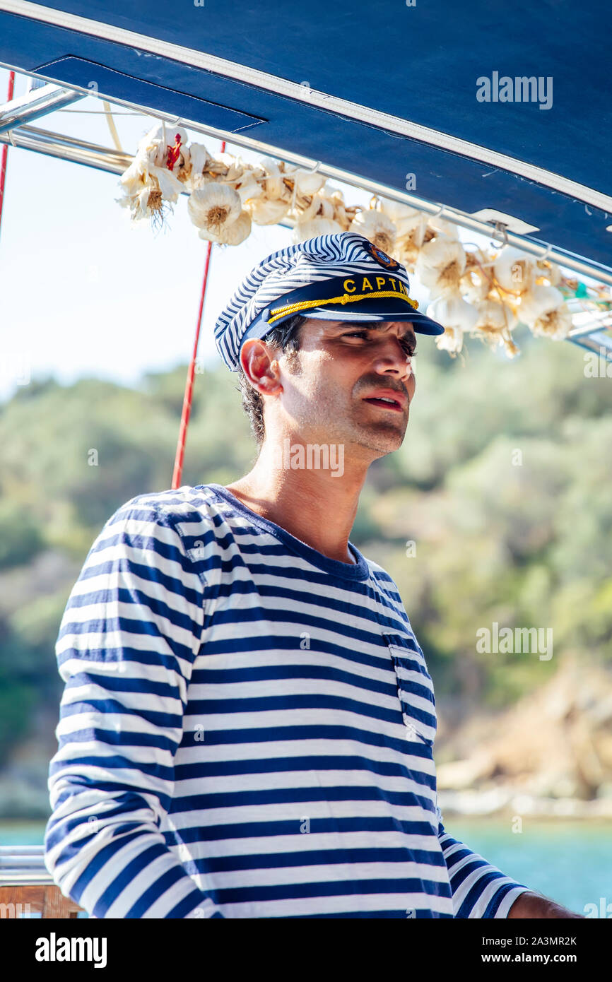 Hübscher junger Mann mit Kapitän Kappe auf einem Segelboot am Meer auf einem suuny Tag Stockfoto