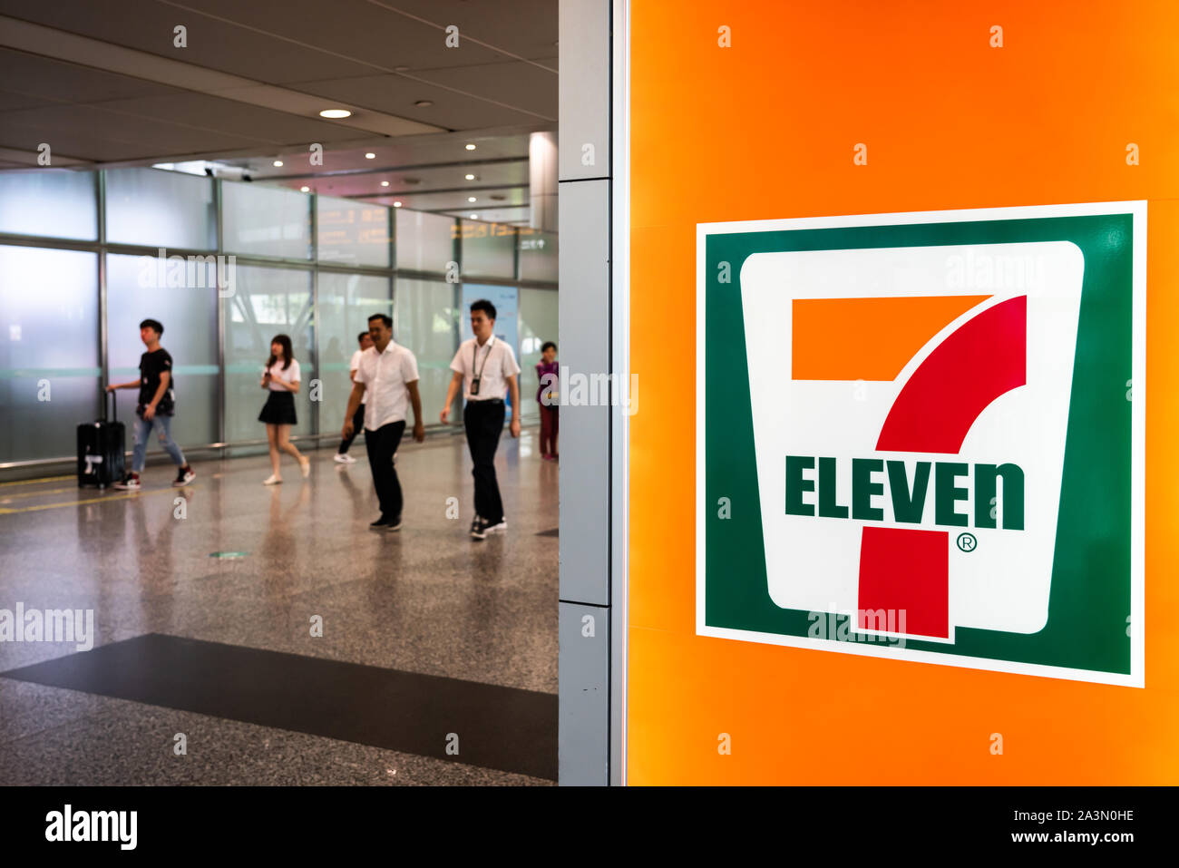 Fußgänger vorbei an einem Japanischen U.S. international Convenience store Kette, 7-Eleven in Guangzhou. Stockfoto