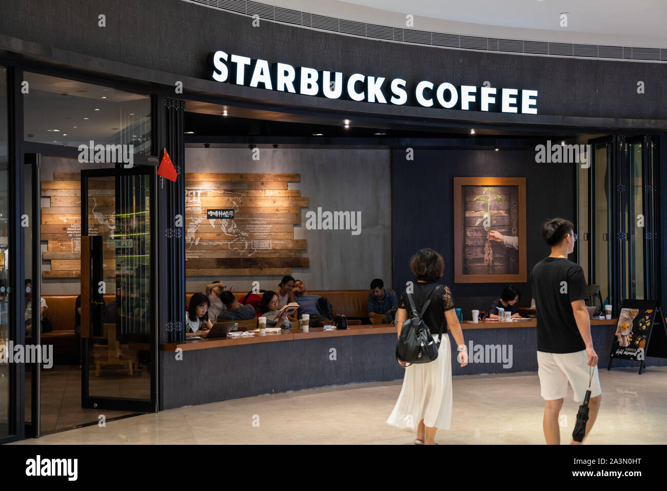 Fußgänger vorbei an einer amerikanischen Kaffee und Kaffeehaus Kette, Starbucks Stores in Guangzhou. Stockfoto