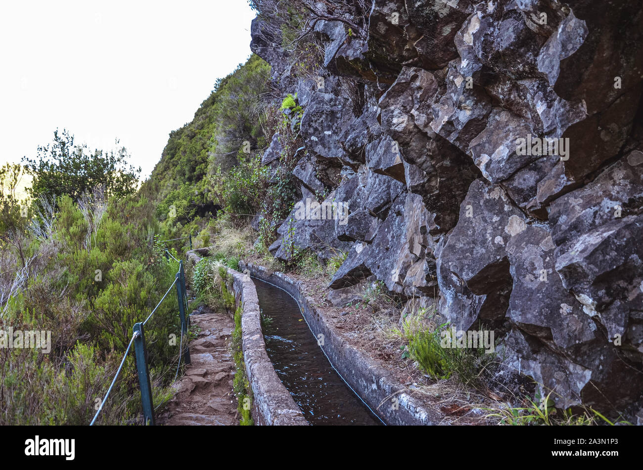 Levada 25 Fontes auf der Insel Madeira, Portugal. Das Bewässerungssystem Canal, Wanderweg, grünen Bäumen und Felsen. Beliebte Touristenattraktion, Wanderziele. Portugiesische Landschaft. Trekking. Stockfoto