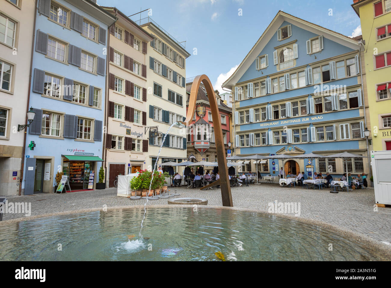 Straße Münsterhof in der Altstadt von Zürich mit öffentlichem Brunnen, Restaurants mit Außenterrassen und bunten Gebäuden Stockfoto