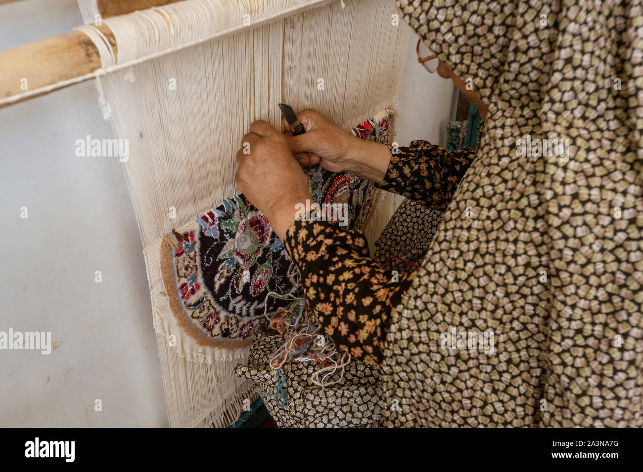 Isfahan, Iran - 2019-04-12 - Frau schafft dekorative Wolldecke auf eine manuelle Webstuhl. Stockfoto