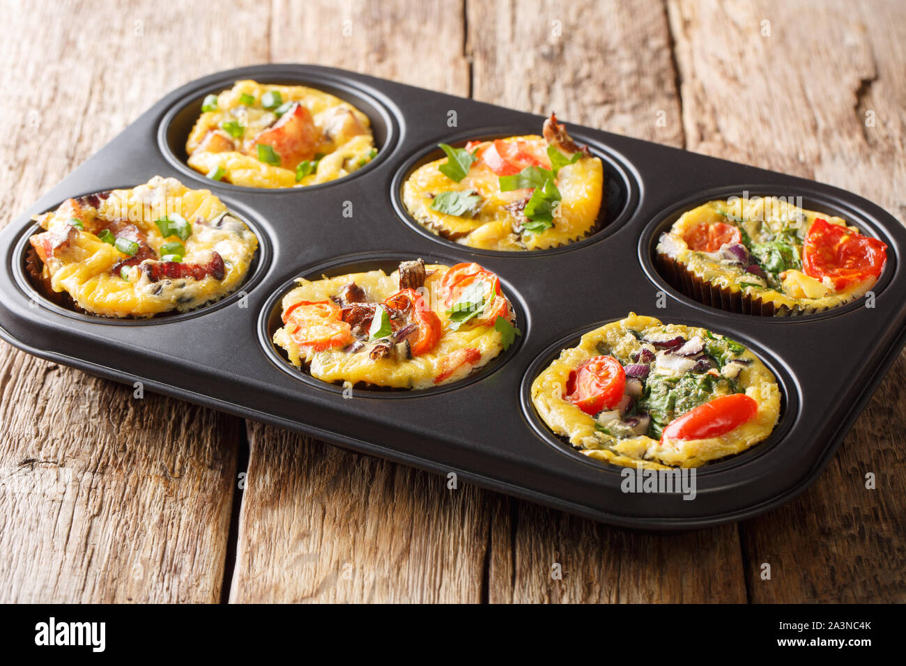 Rezept für Frühstück ei Muffins mit Gemüse, Käse, Speck und Pilzen close-up in einer Auflaufform auf den Tisch. Horizontale Stockfoto