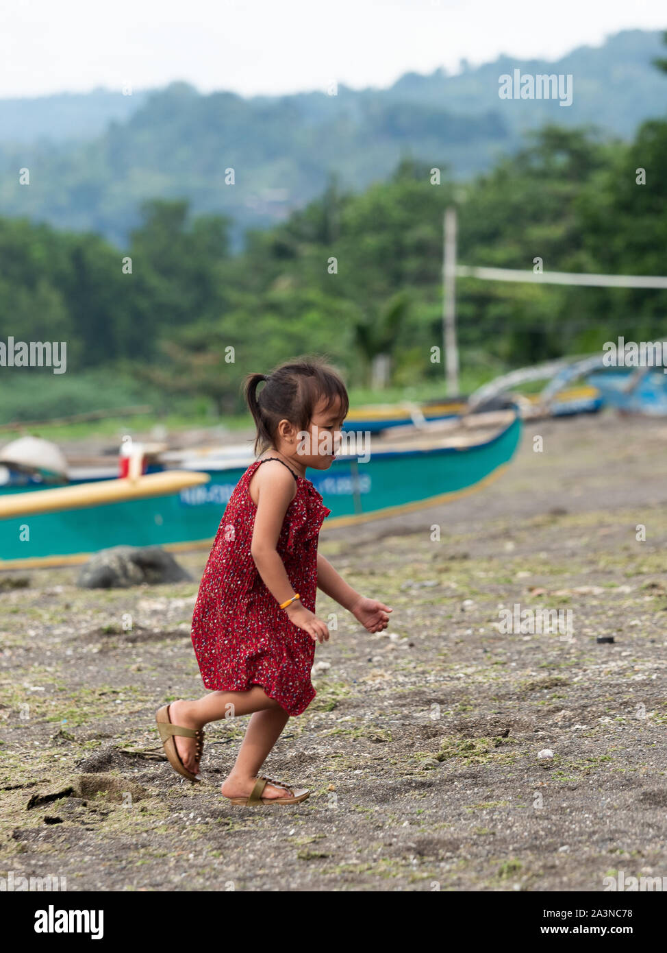 Kinder spielen am Strand mit einem kleinen Fischerboot im Hintergrund. Stockfoto