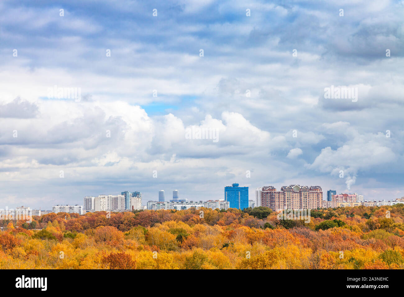 Große weiße Wolken im blauen Himmel über gelb City Park an sonnigen Herbsttag Stockfoto