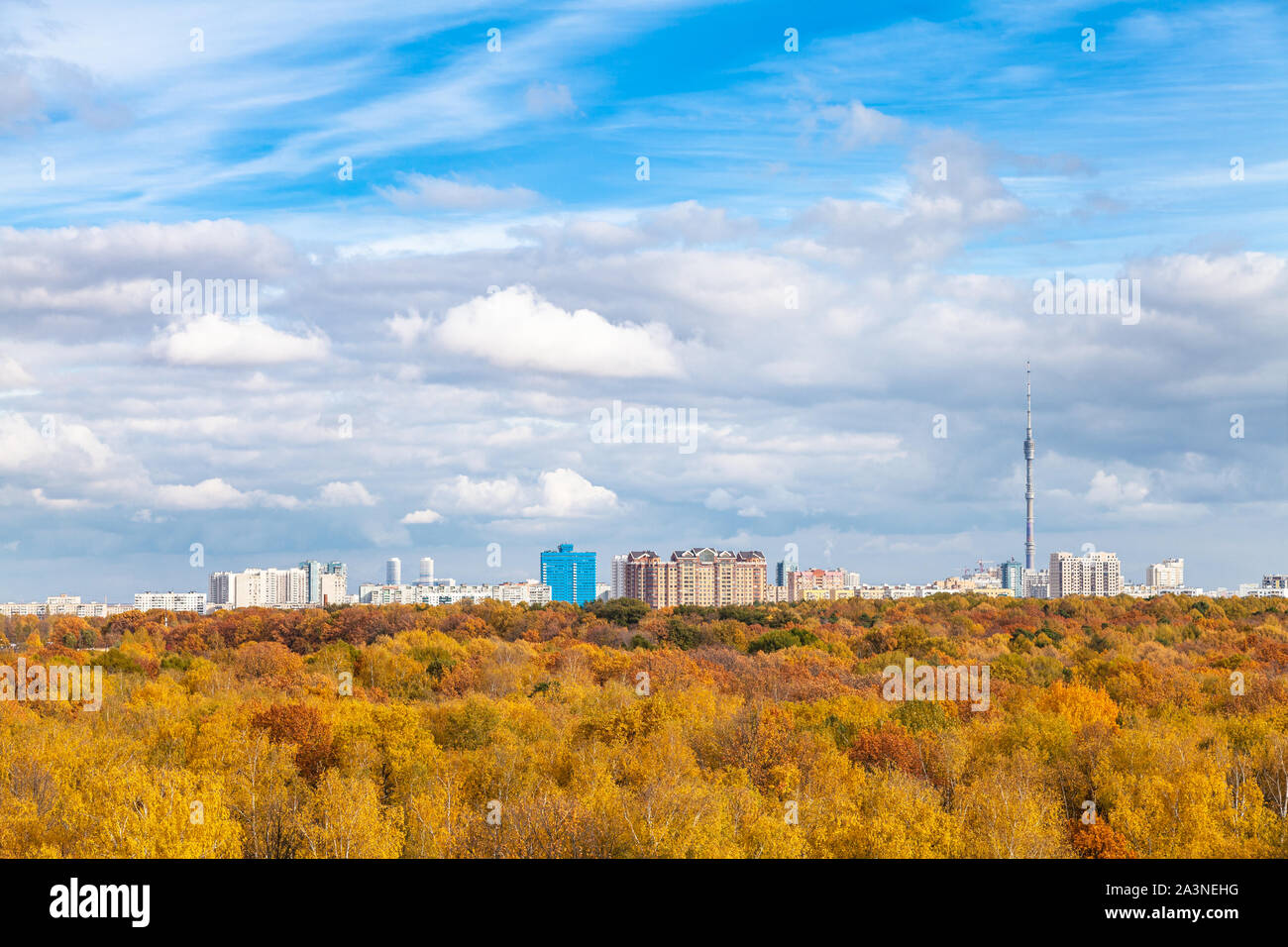 Niedrige weiße Wolken im blauen Himmel über gelb City Park an sonnigen Herbsttag Stockfoto