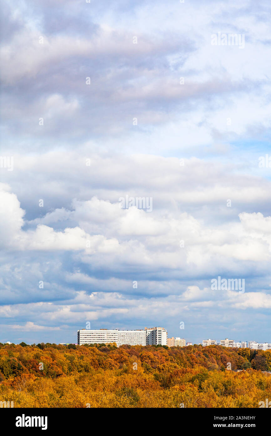 Weiße und graue Wolken im blauen Himmel über gelb City Park an sonnigen Herbsttag Stockfoto