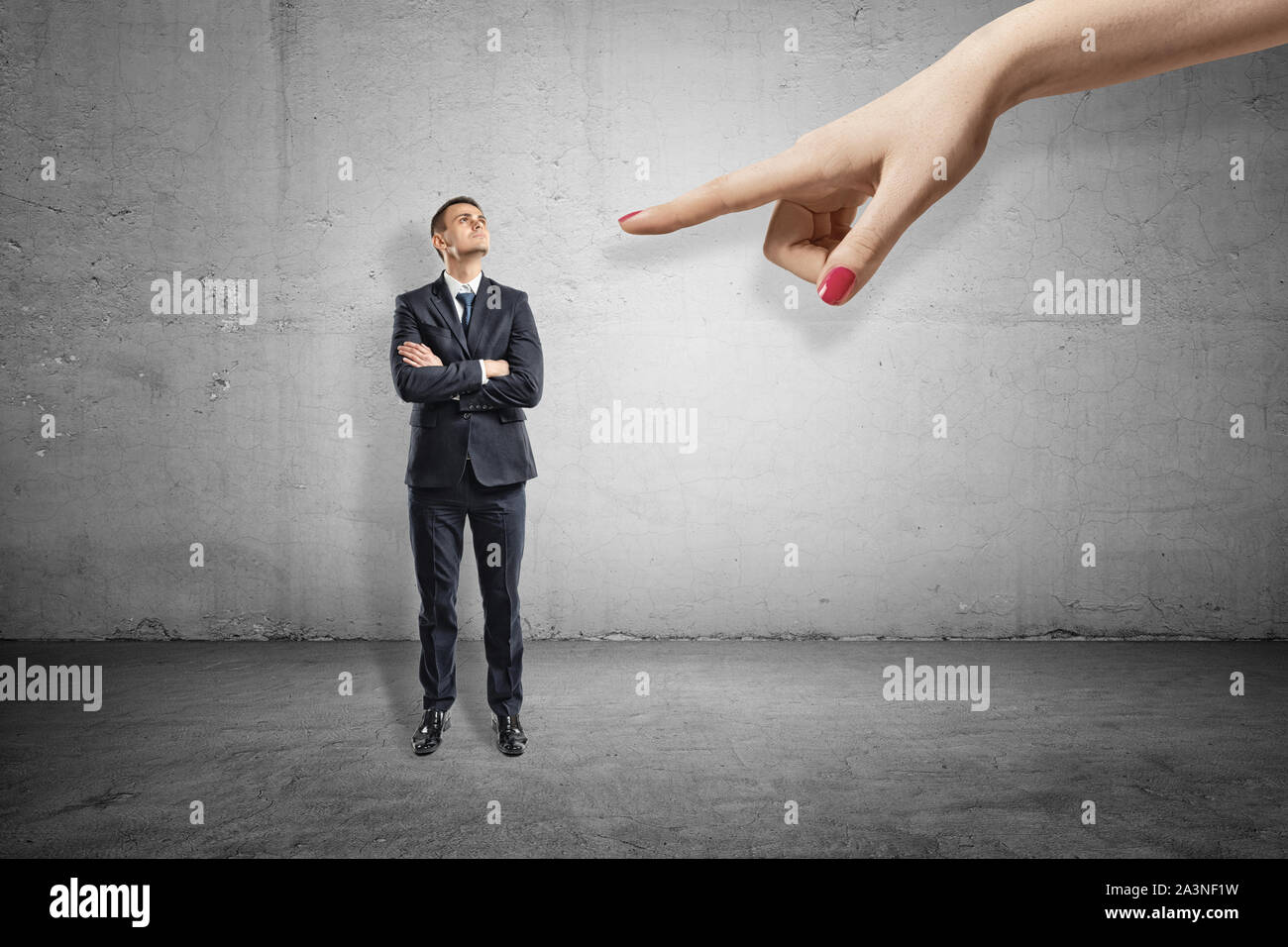 Volle Länge Vorderansicht des kleinen Geschäftsmann stehend, die Arme verschränkt, sah auf der Hand eines großen Frau auf ihn zeigt. Stockfoto