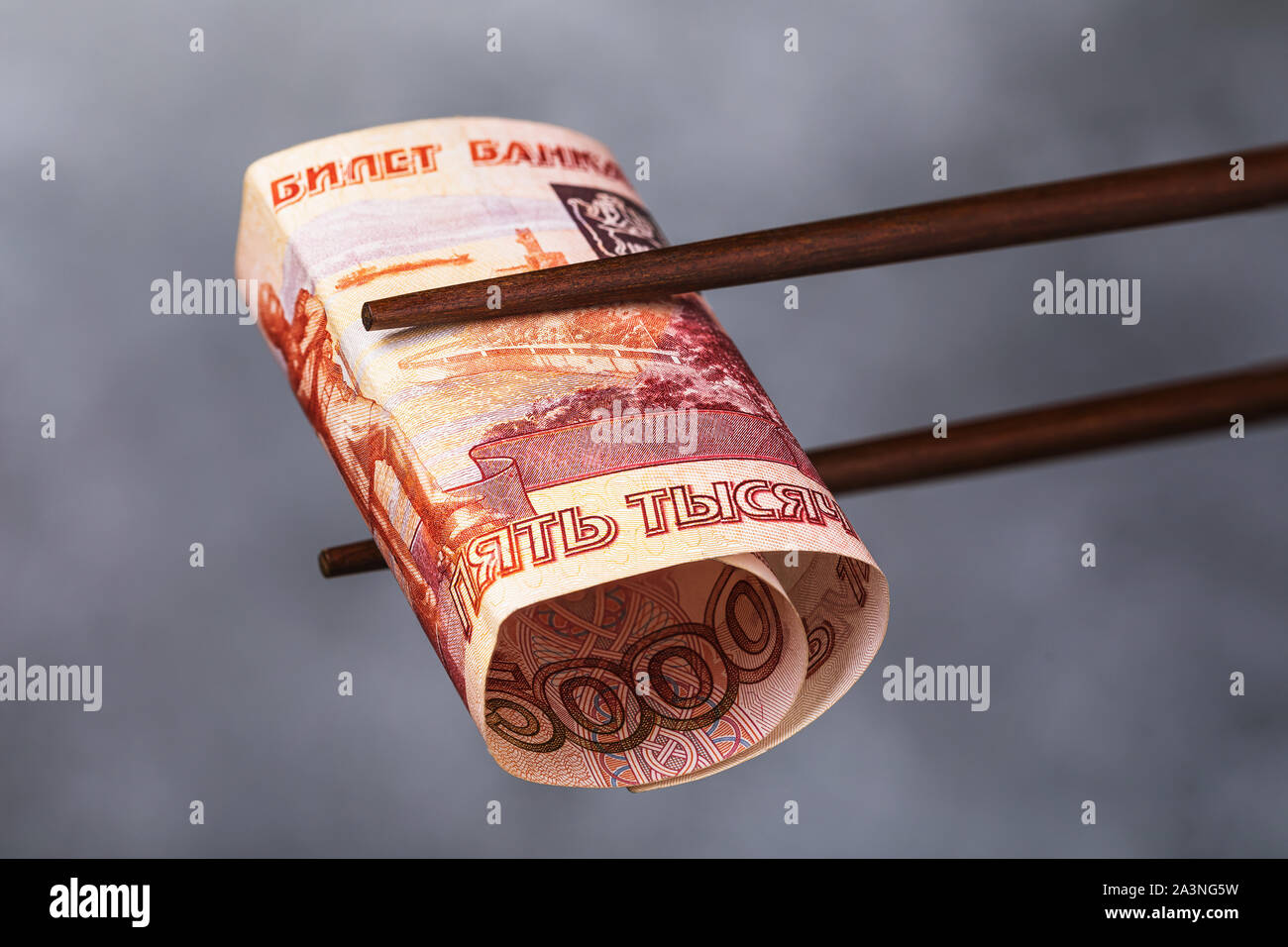 Chinese sticks halten fünf Tausend Rubel, close-up. Das Konzept auf das Verhältnis zwischen Russland und China Stockfoto