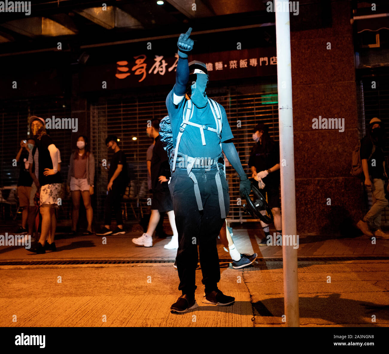 Hongkong, China. 9. Oktober 2019. Großen, ruhigen versammelt Lieder an MOStown Mall in Ma On Shan in Solidarität mit mehreren Wachen, die von der Polizei in dieser Woche verhaftet wurden singen. Später Kleine Gruppe von Demonstranten gingen in der Nähe Shatin gg Polizeistation und rief den Missbrauch bei der Polizei und warf Gegenstände. Die Bereitschaftspolizei später berechnet, aber niemand festgenommen. Demonstrant in Polizei Spotlight macht Geste zu Ihnen. Iain Masterton/Alamy Leben Nachrichten. Stockfoto