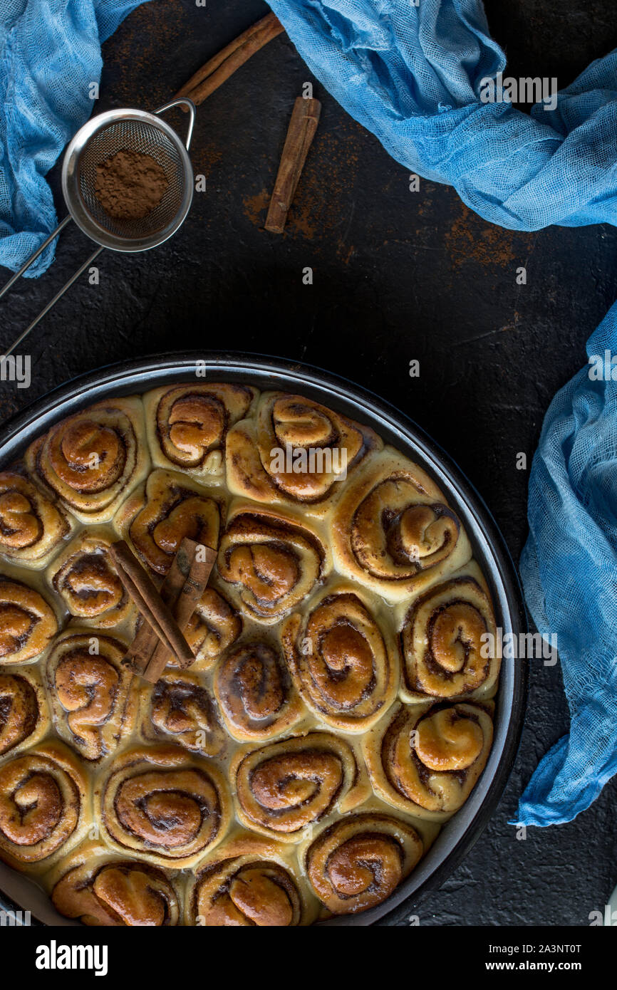 Cinnamon Roll Tarte mit Zuckersirup in vintage Backblech auf schwarzem Hintergrund Stockfoto