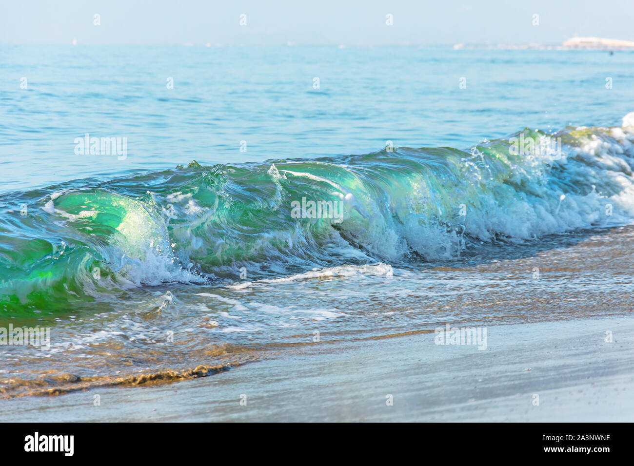 Wellen mit einem grünen Farbton am Strand Stockfoto