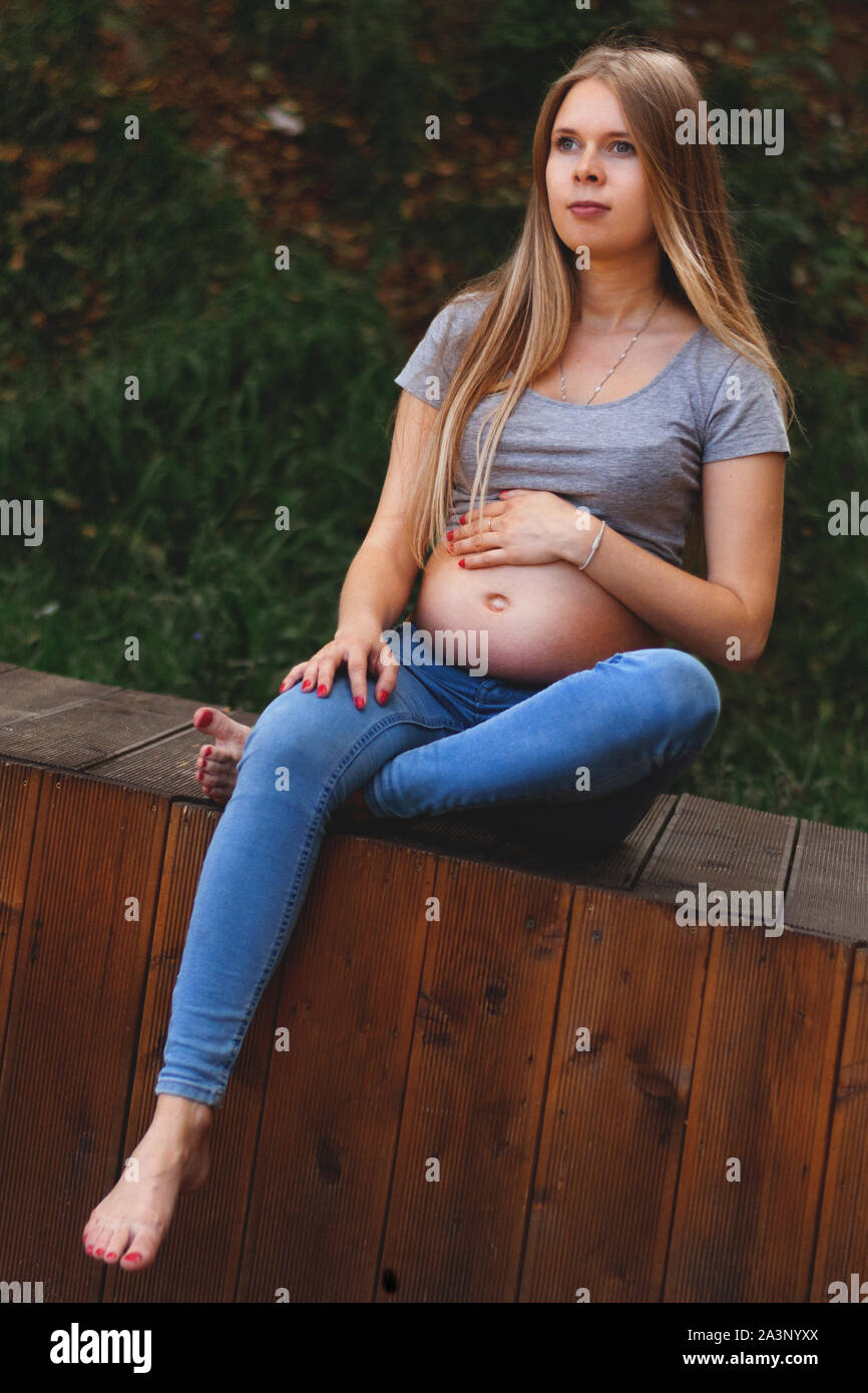 Junge schöne und glückliche schwangere Mädchen Spaziergänge im Park. 2. Trimenon. Die Vorteile der Wandern während der Schwangerschaft, Gesundheit vertikale Foto. Stockfoto
