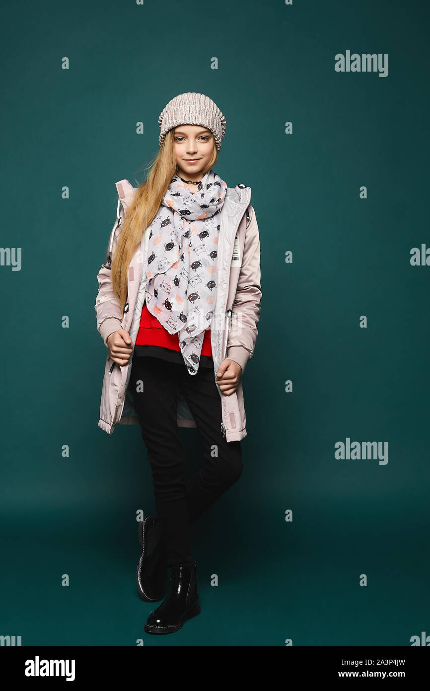 Ein Teenager blonden Model Mädchen in modische Winterbekleidung über den dunklen Hintergrund in voller Länge darstellen. Glückliches Mädchen tragen in Jeans, Stiefel, eine warme Jacke Stockfoto