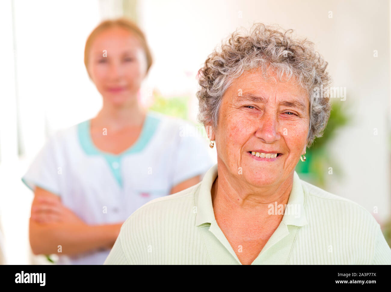 Gerne ältere Frau mit ihrem Betreuer im Hintergrund Stockfoto