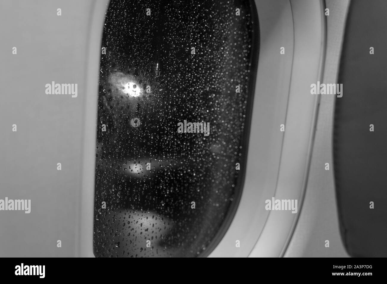 In der Nähe des regen Wassertropfen auf Glas Fenster rahmen Flugzeug Fenster innere Flugzeug und Unschärfe Hintergrund mit Kreis runde Licht bokeh. Stockfoto