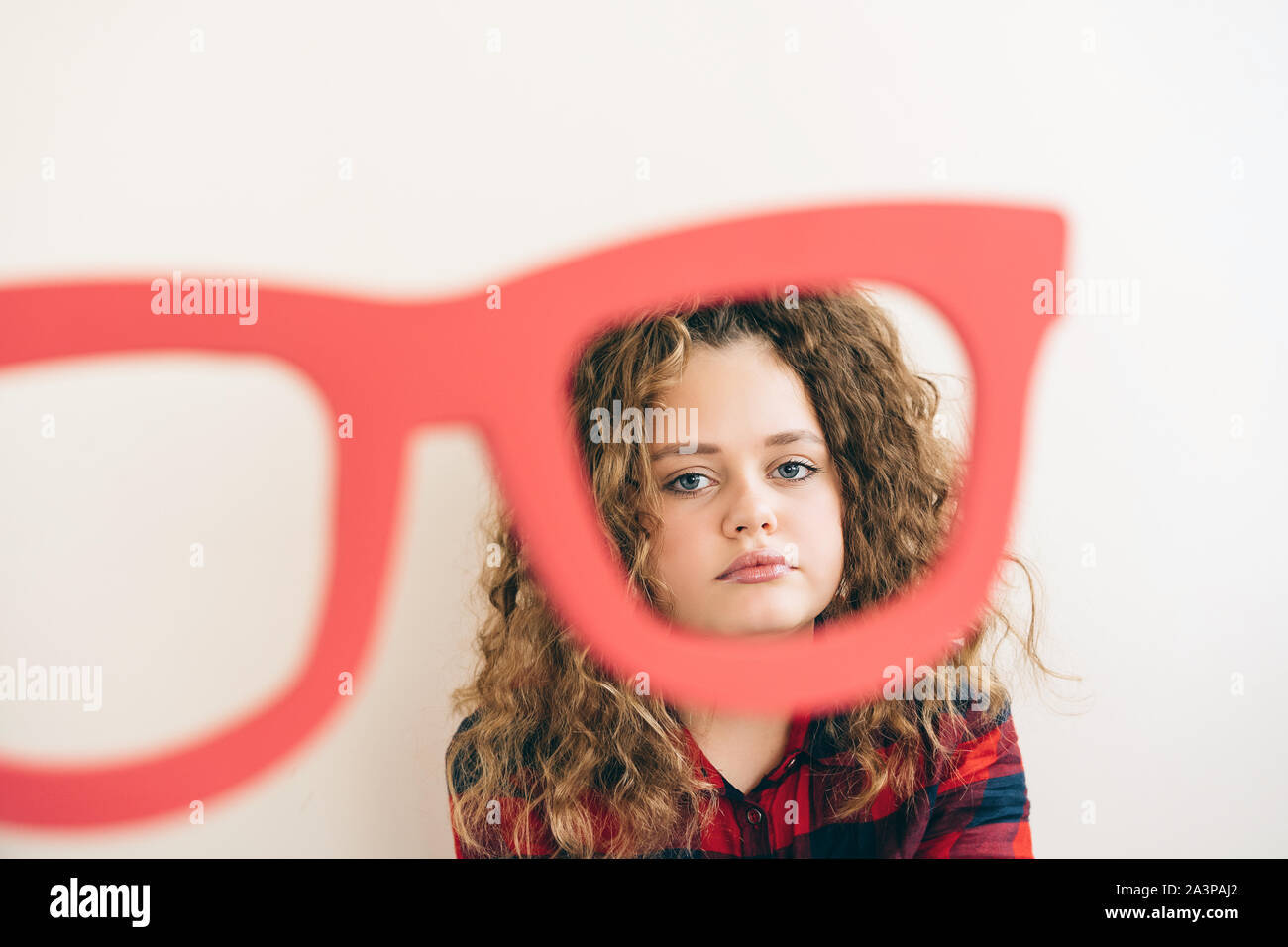 Cute curly Langhaarige blonde Teen Girl Über lustige große Gläser rote Farbe sieht Stockfoto