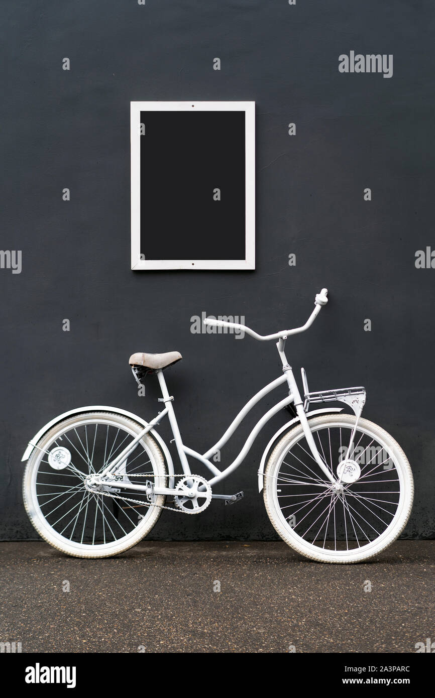 Eine weiß lackierte Fahrradständer gegen eine schwarze Wand Stockfoto