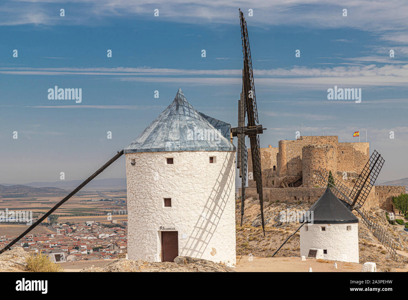 Landschaft in der spanischen Gemeinde Consuegra mit zwei alte Windmühle und das Schloss von La Muela im Hintergrund an einem Sommertag mit bewölktem Himmel Stockfoto