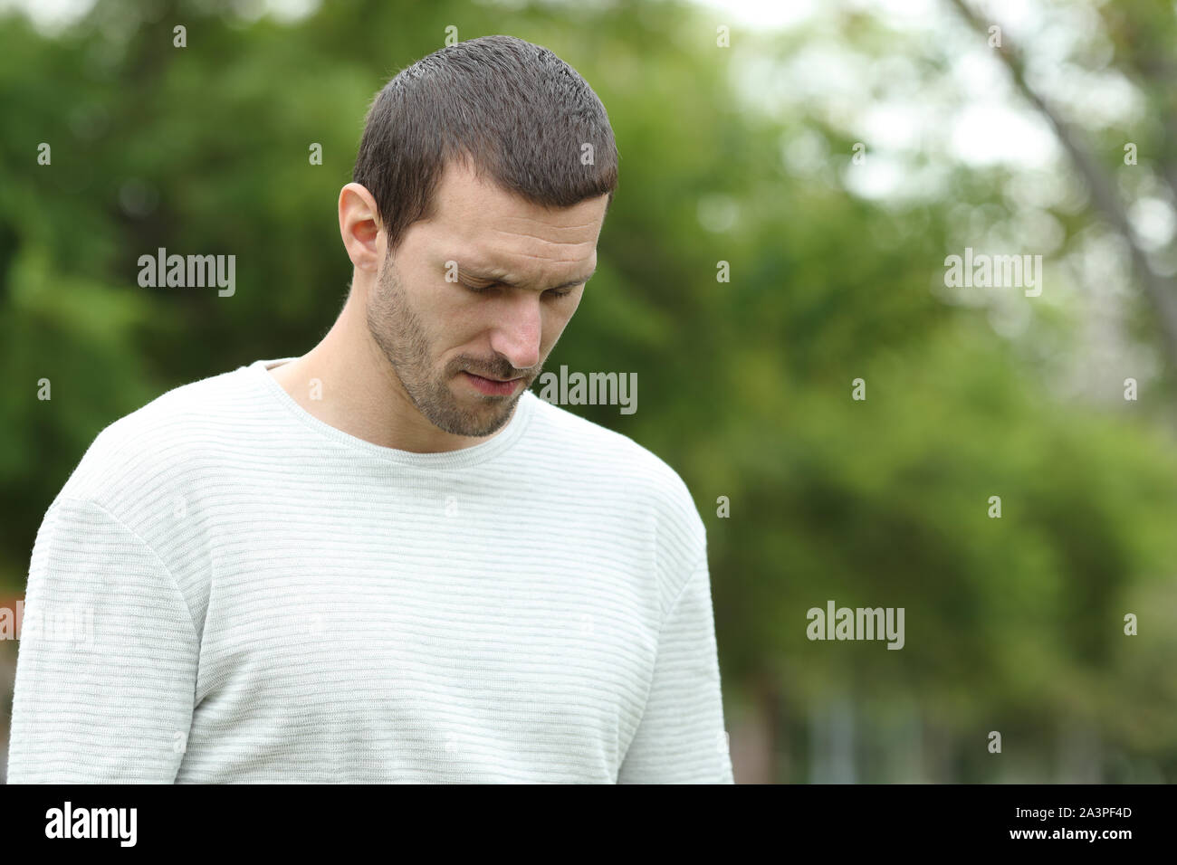 Mann traurig allein zu Fuß nach unten beklagt in einem Park Stockfoto