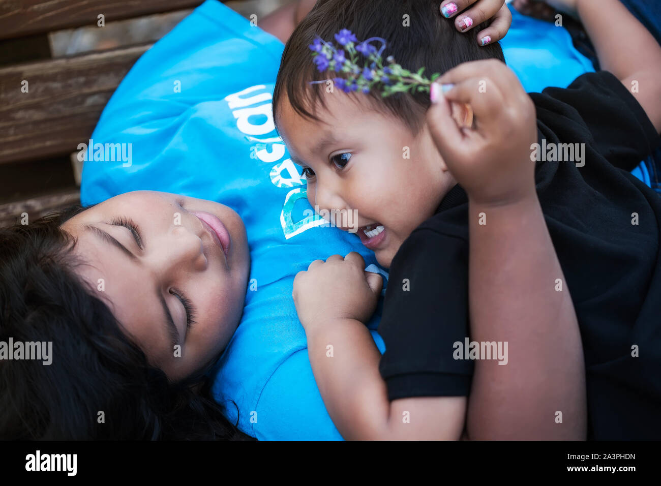 Einen kleinen Bruder, seine ältere Schwester eine Umarmung und der älteren Schwester, freundlich und liebevoll auf ihn zu, während die Festlegung in einer Bank. Stockfoto