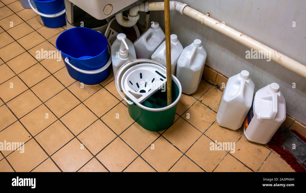 Unordentliche Reiniger Schrank mit Wischmopp und Eimer und Behälter von Reinigungsflüssigkeiten Stockfoto