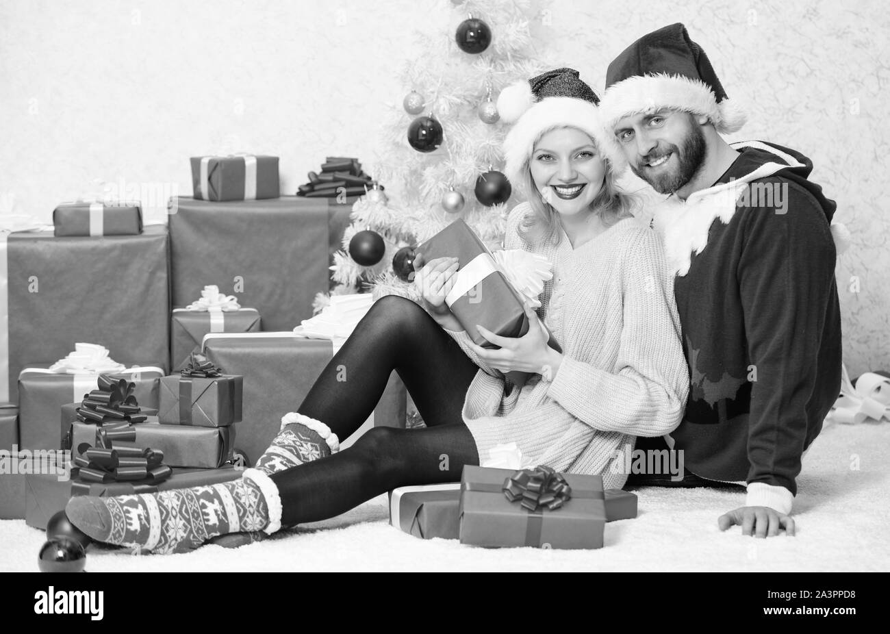 Paar in der Liebe genießen Sie Weihnachten feiern. Feiern Weihnachten zusammen. Paar kuscheln Lächeln beim Auspacken der Geschenke mit Weihnachtsbaum Hintergrund. Weihnachten mit der Familie Tradition. Stockfoto