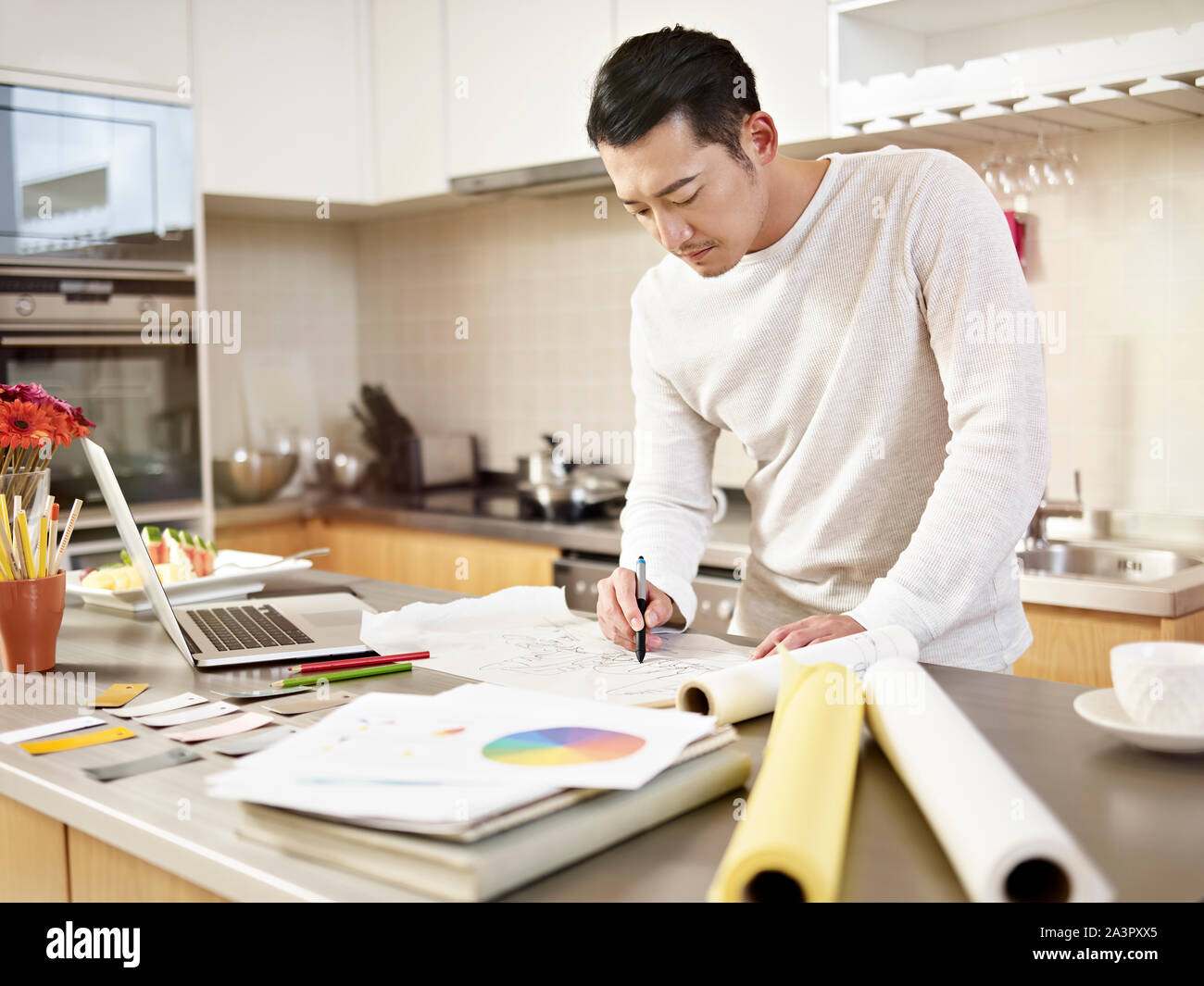 Junge asiatische Designer zu Hause Zeichnung an Papier auf den Küchentisch Stockfoto