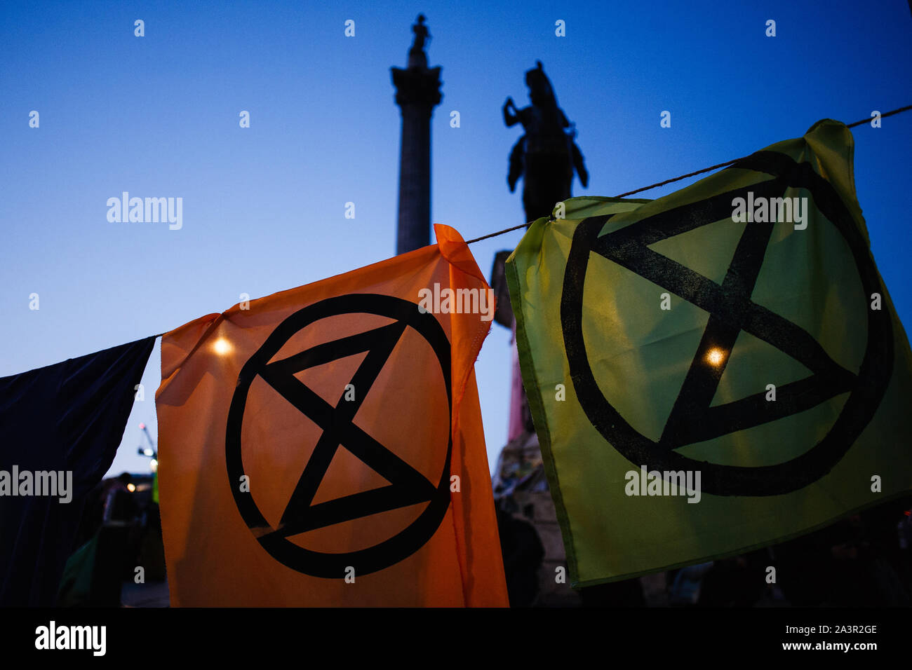 Blätter aus Stoff, die das Logo des Klimawandels Aktivist Gruppe Aussterben Rebellion (XR) hängen von einer Wäscheleine auf dem Trafalgar Square als die Dunkelheit am zweiten Tag von der Gruppe "Internationale Rebellion' in London fällt. Von frühen Dienstag Abend der Metropolitan Police berichteten, dass insgesamt 531 Festnahmen so weit über den zwei Tagen der Proteste in der Stadt gemacht worden war, mit Polizisten, damit sich alle Personen und Zelte, die von vielen Seiten von Aktivisten gestern genommen. Ähnliche Blockaden vom Aussterben Rebellion im April, an Standorten mit der Oxford Circus und Waterloo Bridge, s Stockfoto