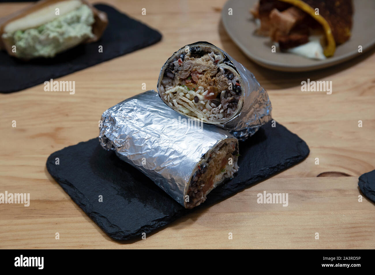 Beef Burrito mit Reis und Bohnen in Silber Papier auf Steinplatte umhüllt, typisch Lateinamerikanische Küche Stockfoto