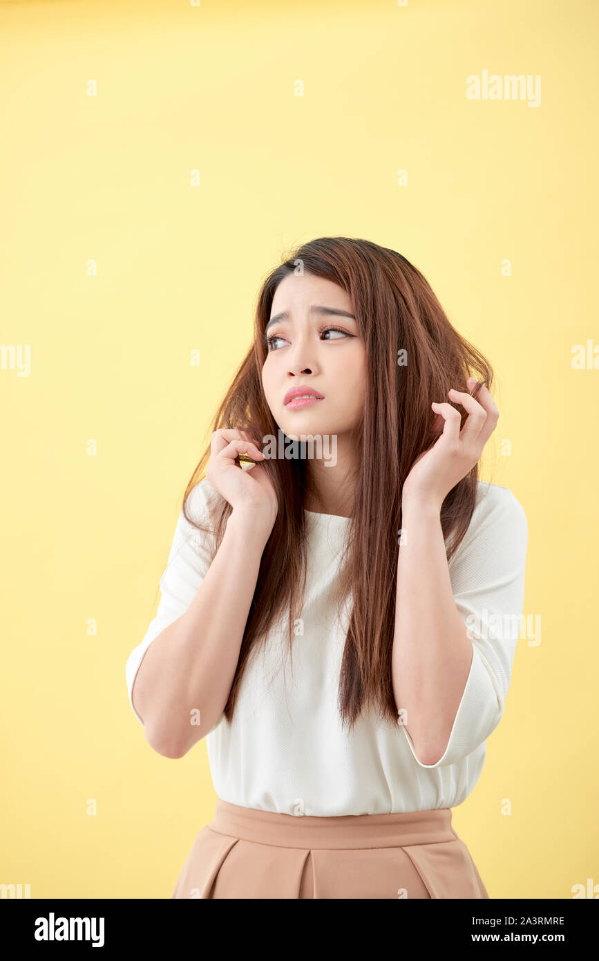 Junge asiatische Frau ihr Haar und enttäuschend Zustand ihrer Haare bürsten Stockfoto