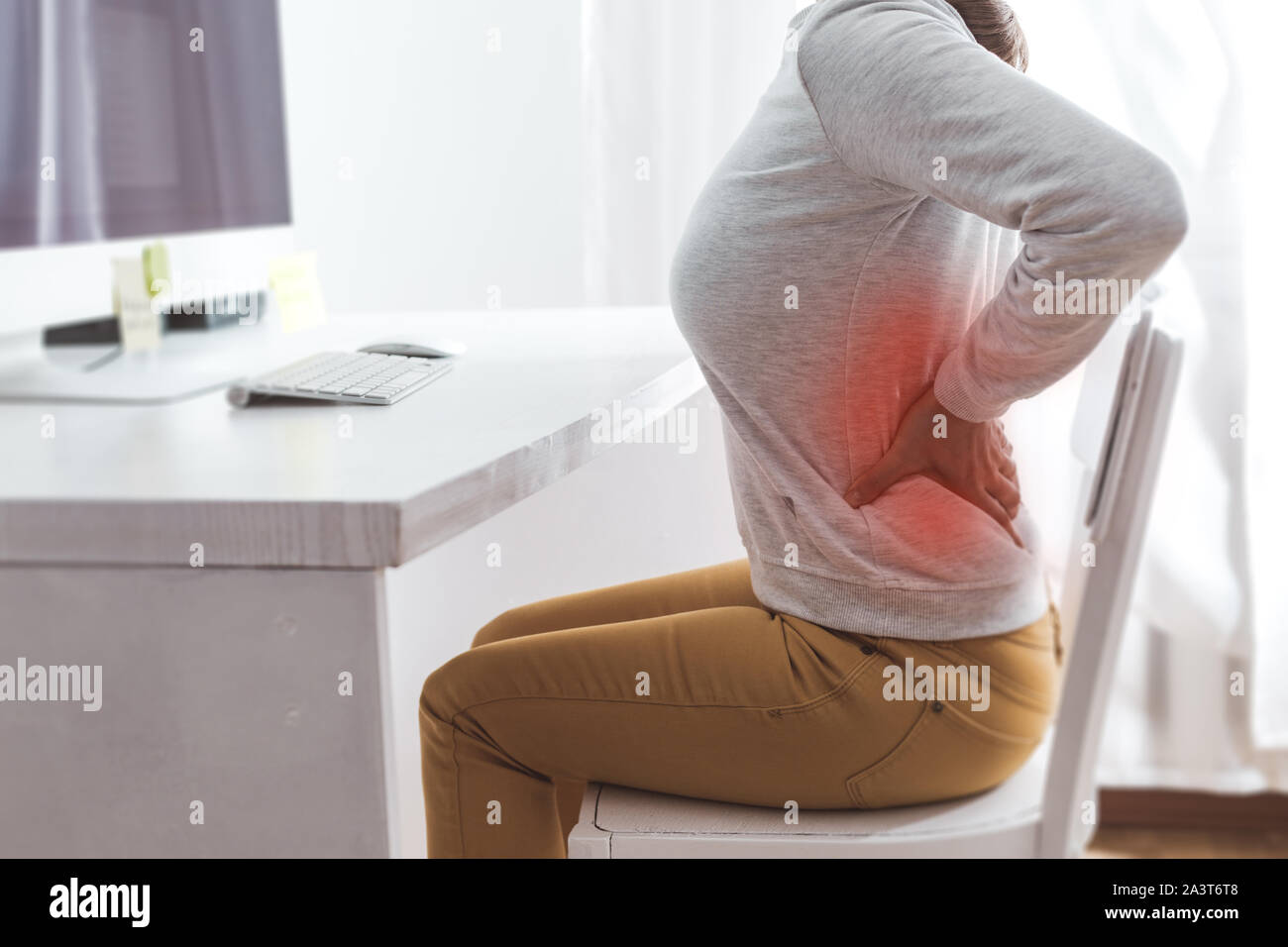 Nierenschmerzen. Schmerzen im Rücken einer Frau von der Arbeit am Computer. Stockfoto