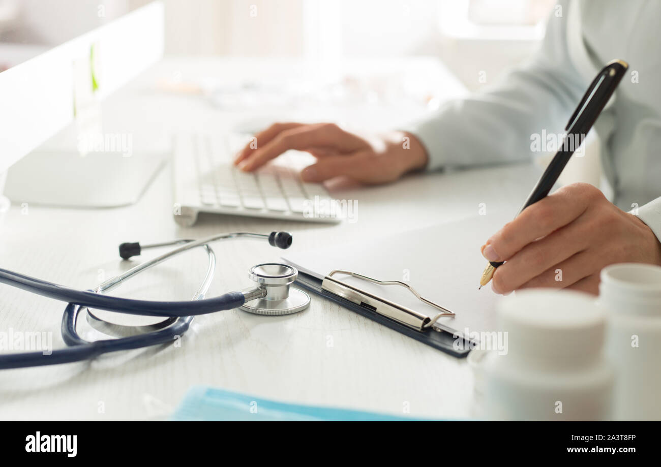 Frau Doktor schreibt einen medizinischen Bericht im Büro der Klinik. Stockfoto