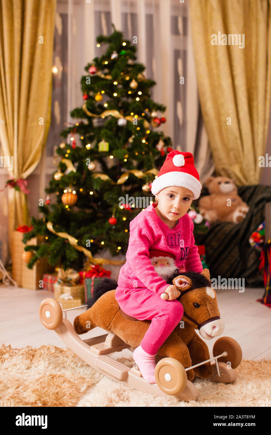 Glückliches Mädchen ein Pferd Reiten vor dem Weihnachtsbaum zu Hause. Stockfoto
