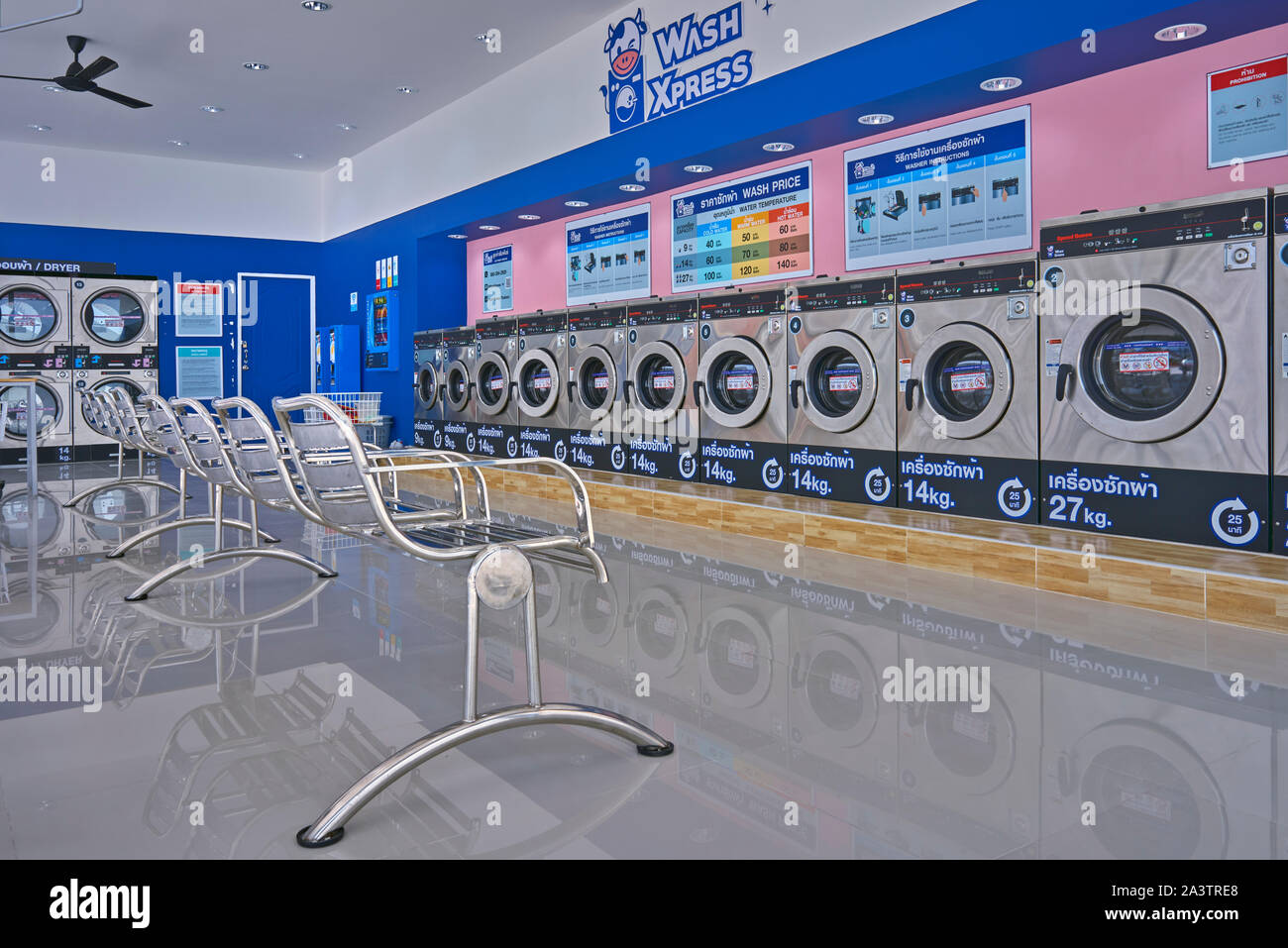 Waschsalon mit Waschmaschinen und Sitzgelegenheiten für Kunden. Thailand Südostasien Stockfoto