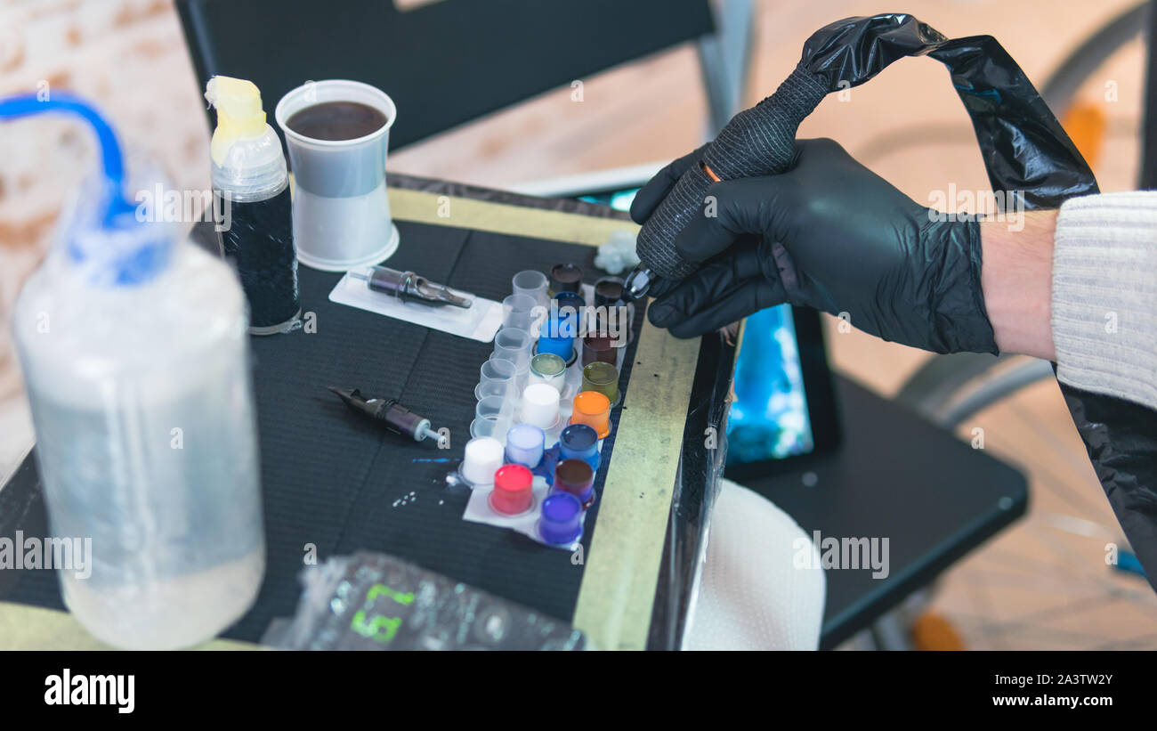 Close-up Tattoo artist Arbeitsplatz teilen und Farbe, Maschinen und andere Geräte. Professionelle Tätowierer Tätowierung arbeiten im Studio. Prozess der Mak Stockfoto